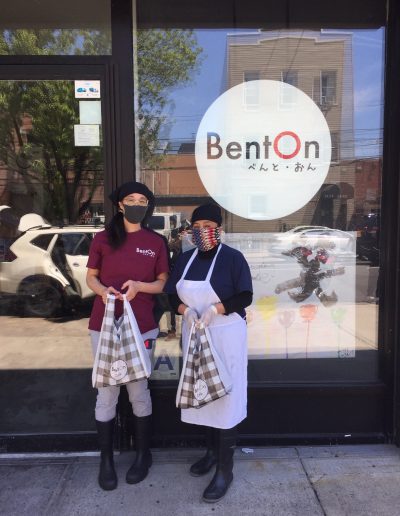 Two BentOn workers standing outside of BentOn wearing masks