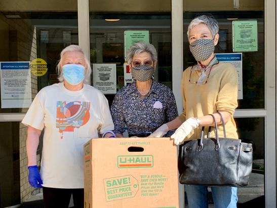 Three people wearing masks posing outside a building