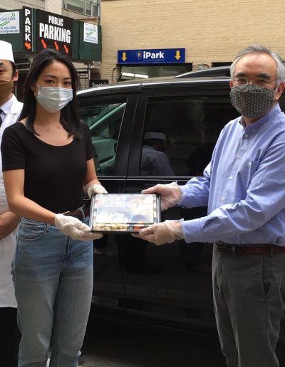 Five volunteers wearing masks presenting a food package