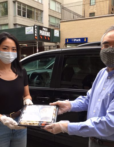 Two people wearing masks passing a food delivery between them