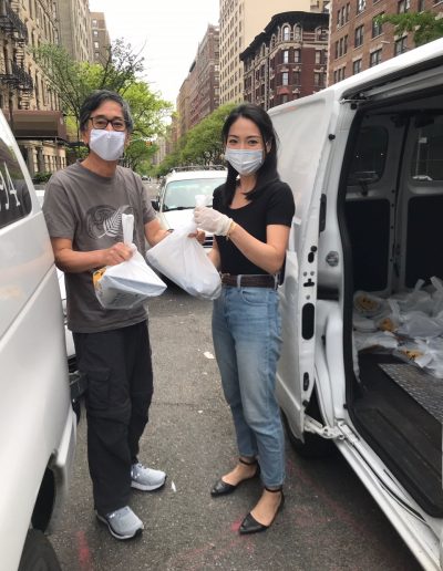 Two volunteers wearing masks and holding food packages
